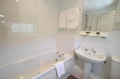 a white bathroom with a sink and a bath tub at The Colonsay Hotel in Isle of Colonsay