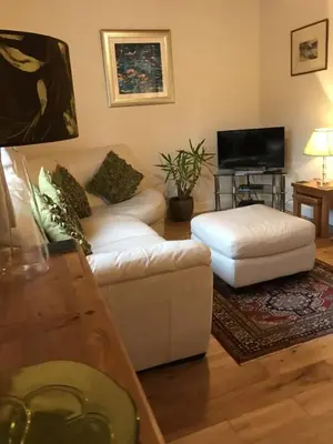 a living room with a white couch and a ottoman at Kilchurn Suites in Loch Awe