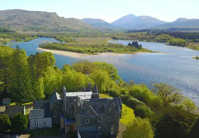 an aerial view of a castle next to a lake at Kilchurn Suites in Loch Awe