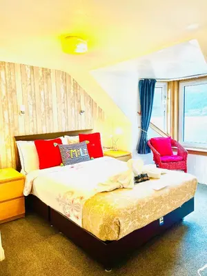 a bedroom with a bed and a red chair at Rowantreebank Bed and Breakfast in Arrochar