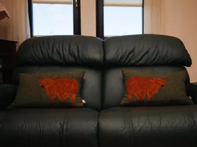 a black leather couch with two pillows on it at Shenavallie Farm in Benderloch