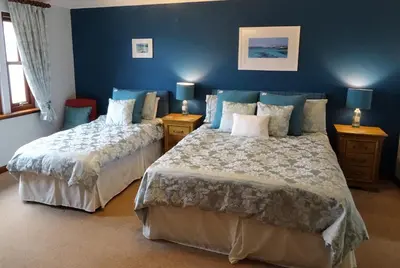 two beds in a bedroom with blue walls at Ardno House B & B in Glencoe