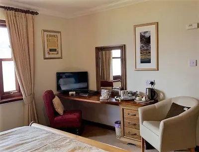 a bedroom with a desk with a computer and a chair at Ardno House B & B in Glencoe