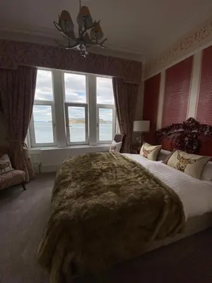 a bedroom with a large bed with a blanket on it at Altavona House in Oban