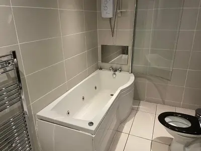 a white bath tub in a bathroom with a toilet at Glazert Country House Hotel in Lennoxtown