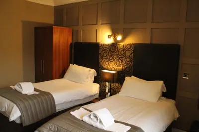 a hotel room with two beds with white sheets at Glazert Country House Hotel in Lennoxtown
