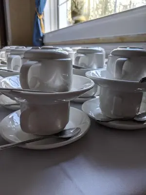 a row of white cups and saucers on a table at Glazert Country House Hotel in Lennoxtown
