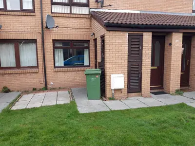 a house with a green trash can in the yard at Hardgate Gardens in Glasgow