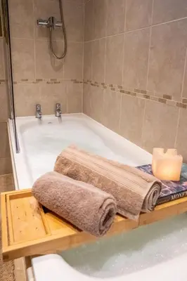 a bathroom with a bath tub with a candle and towels at Cottage Apartment in Dunblane