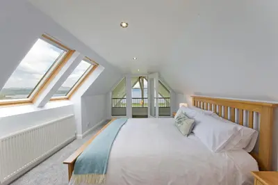 a bedroom with a large bed with windows at Seabank House in Oban
