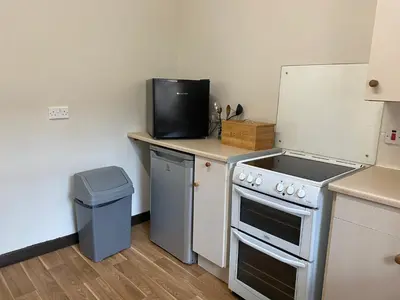 a kitchen with a stove and a tv on a counter at Welltrees Apartments 8 Dailly Road in Maybole