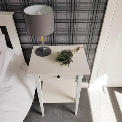 a white nightstand with a lamp and a plant on it at Bespoke Tours Scotland Accommodation @ Morrison Street in Edinburgh