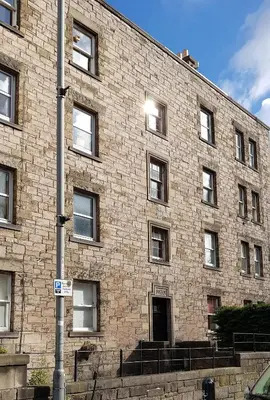 a large brick building with a door and stairs at Bespoke Tours Scotland Accommodation @ Morrison Street in Edinburgh
