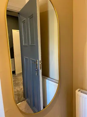 a mirror with a blue door in a bathroom at Raniven in Oban
