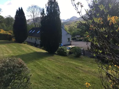 a white house in a field with trees and a yard at Invercreran Lodge Luxury Bed & Breakfast in Appin