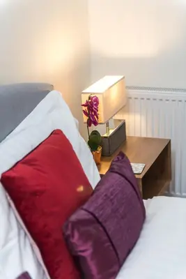a bed with red pillows and a table with a lamp at Charming, Central & Spacious Georgian 3 bed APT in Edinburgh