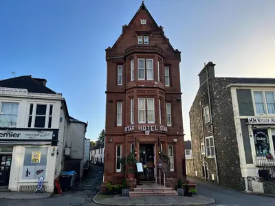 a tall brick building with a clock tower on a street at The Famous Star Hotel Moffat in Moffat