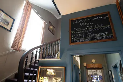 a staircase with a sign on the wall and a stair case at The Famous Star Hotel Moffat in Moffat