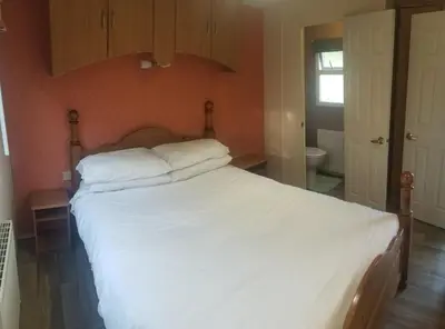 a bedroom with a large bed with white sheets at Hawthorn Self Catering Cottages in Benderloch