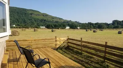 two chairs sitting on a deck looking at a field at Hawthorn Self Catering Cottages in Benderloch