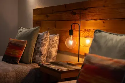 a bedroom with a bed with a lamp and pillows at The Trout Fly Guest House in Port Ellen