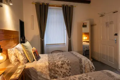 a hotel room with two beds and a window at The Trout Fly Guest House in Port Ellen