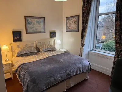 a bedroom with a bed and a large window at Glades House in Glasgow