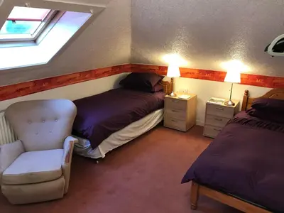 a bedroom with two beds and a chair and a window at Glades House in Glasgow
