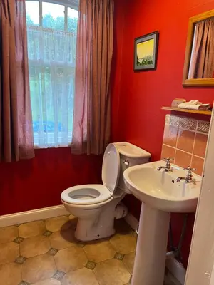 a red bathroom with a toilet and a sink at The Gardener's House in Covington