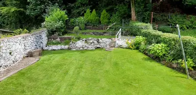 a garden with a stone wall and green grass at One Oban in Oban