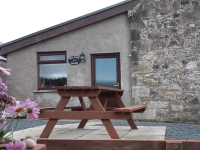 a picnic table in front of a building at Old Stable Cottage in Uplawmoor
