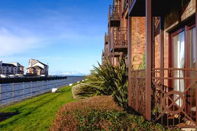 a building with a balcony next to a body of water at The Mariners in Ayr