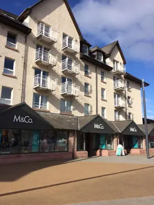 a large apartment building with a store in front of it at Lismore House in Oban