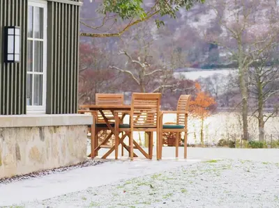 a wooden table and chairs sitting outside of a house at Dalveich Cottage, hot tub, 2 bedroom, Lochearnhead in Lochearnhead