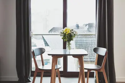 a table with chairs and a vase of flowers on it at The Ranald Apartments in Oban