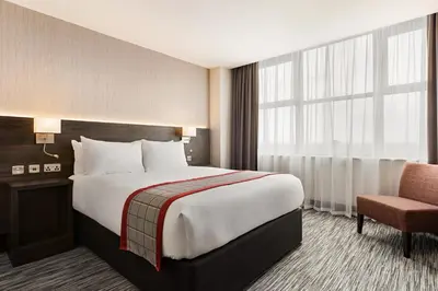 a hotel room with a large bed and a chair at Ramada East Kilbride in East Kilbride