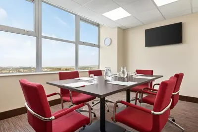 a conference room with a table and red chairs at Ramada East Kilbride in East Kilbride