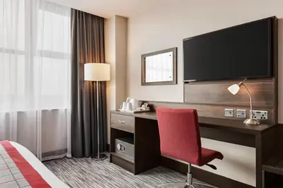 a hotel room with a desk with a tv and a red chair at Ramada East Kilbride in East Kilbride