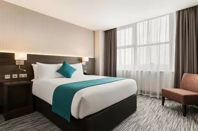 a hotel room with a large bed and a chair at Ramada East Kilbride in East Kilbride