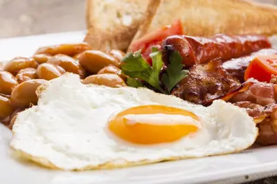 a plate of breakfast food with eggs bacon beans and toast at Loch Leven Hotel & Distillery in Glencoe