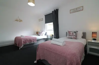 a room with two beds with pink sheets and a window at Signature - Gartlea House in Airdrie