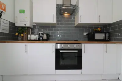 a kitchen with white cabinets and a stove top oven at Signature - Gartlea House in Airdrie