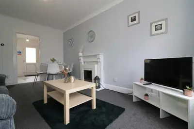 a living room with a flat screen tv and a table at Signature - Gartlea House in Airdrie
