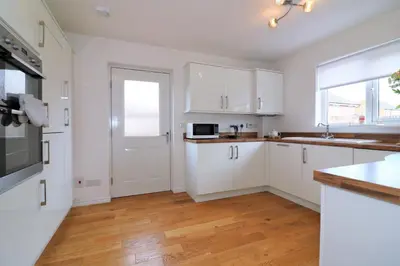 a white kitchen with white cabinets and a wooden floor at Signature - Morrison House in Glasgow