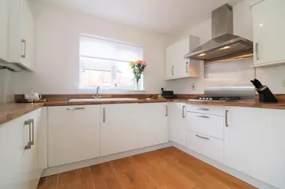 a white kitchen with white cabinets and a window at Signature - Morrison House in Glasgow