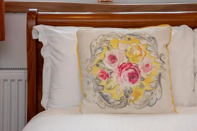 a pillow with a flower pattern on it on a bed at Mandarin Premier Apartments D 2 Bed Apt 1st Floor in Oban
