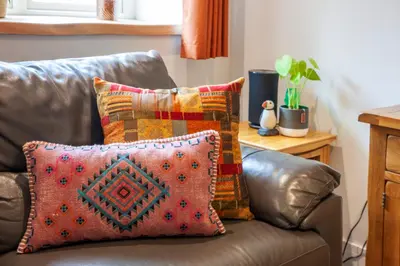 a brown leather couch with a pillow on it at Mandarin Premier Apartments D 2 Bed Apt 1st Floor in Oban