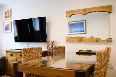 a dining room with a table and a tv at Mandarin Premier Apartments D 2 Bed Apt 1st Floor in Oban