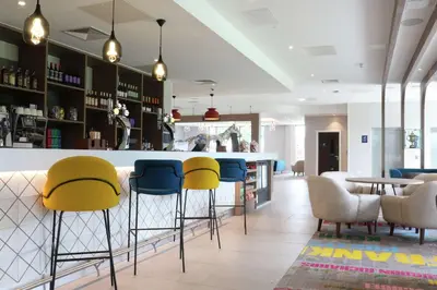 a bar with yellow and blue chairs in a restaurant at Hampton By Hilton Hamilton Park in Hamilton