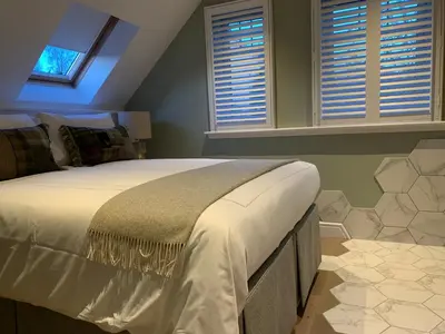 a bedroom with a large bed and two windows at Bagpipers Luxury Hideaway Glencoe Ballachulish Highlands Near Fort William in Glencoe
